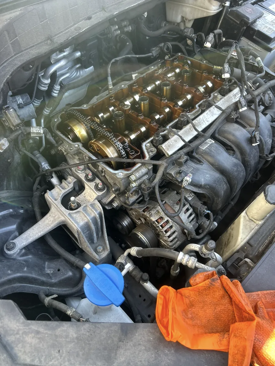 Engine bay with the valve cover removed, camshafts and timing chain visible